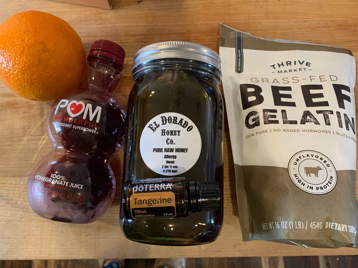 Pomegranate juice, beef gelatin and an orange on a counter