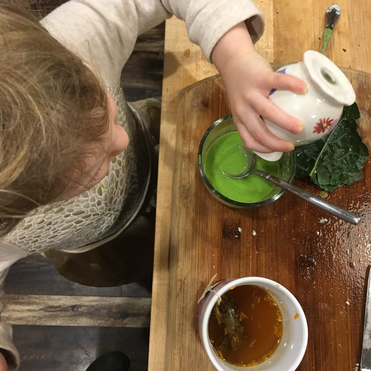 A child helping blend a green smoothie