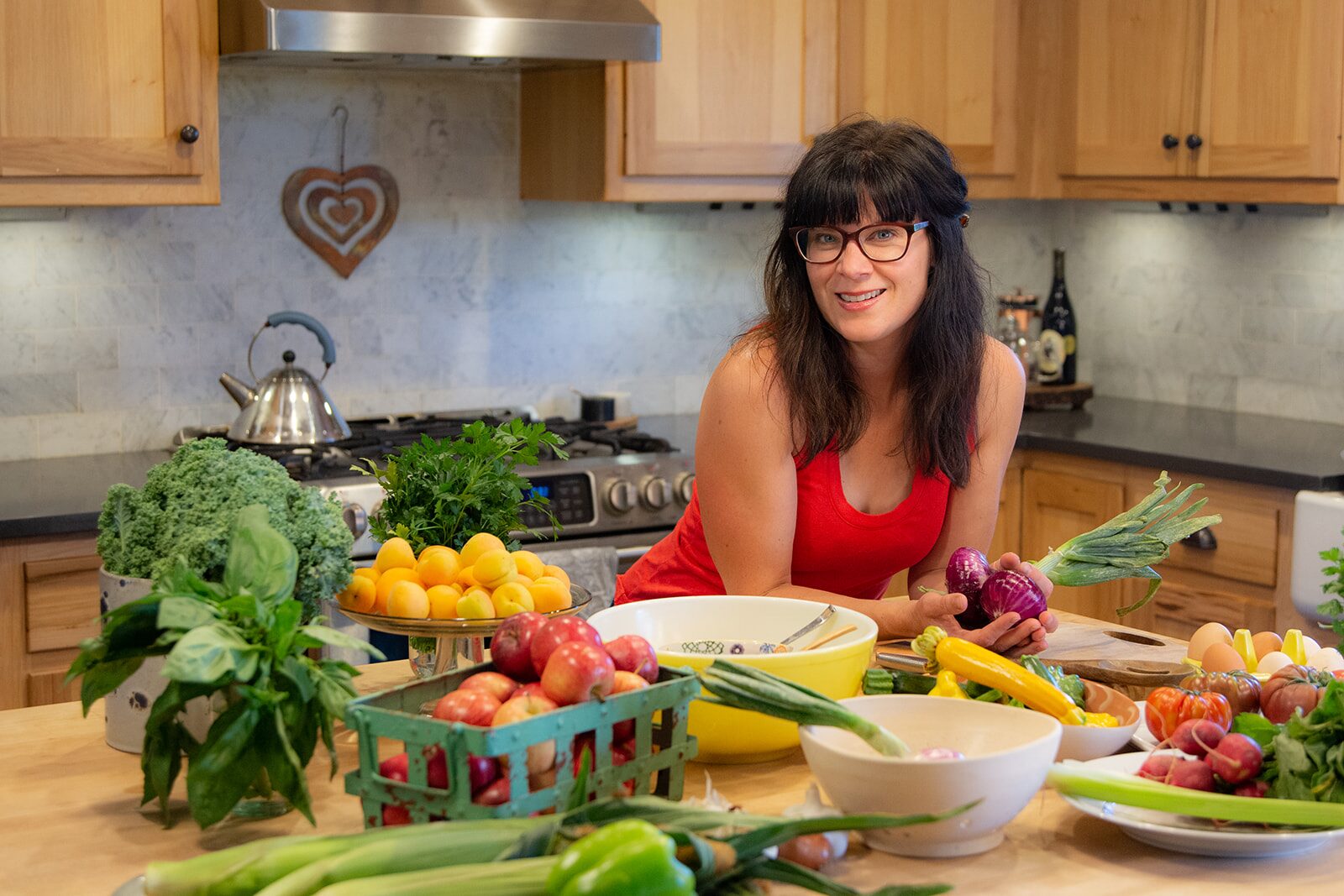 Chelsea Britton at her kitchen counter surrounded by fresh vegetables