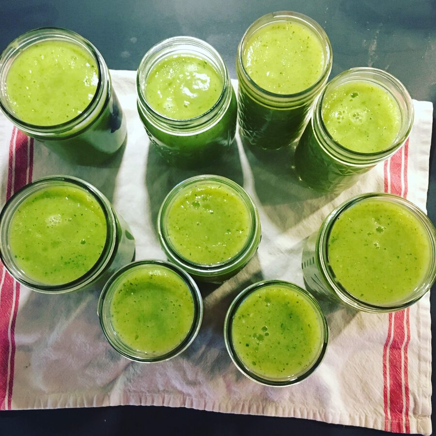 Jars of green smoothie lined up on a towel