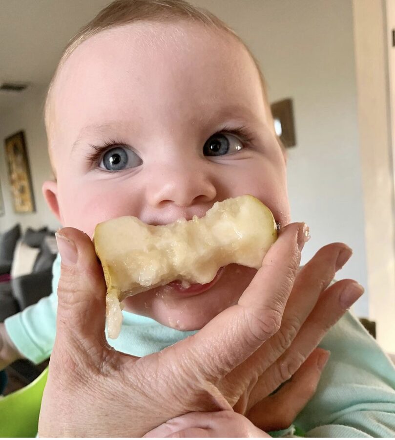 A baby eating a slice of apple