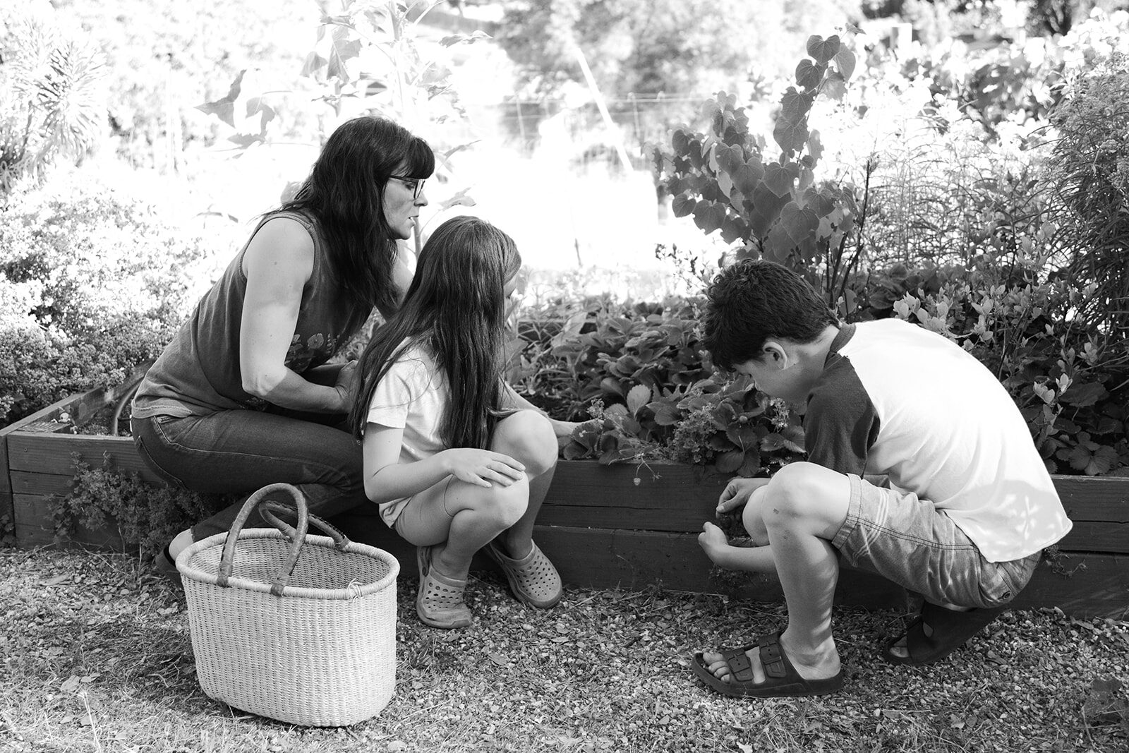Chelsea kneeling in the garden with her children, black and white