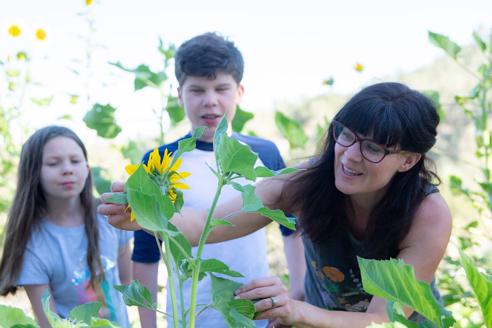 Chelsea and her children in the garden holding a sunflower